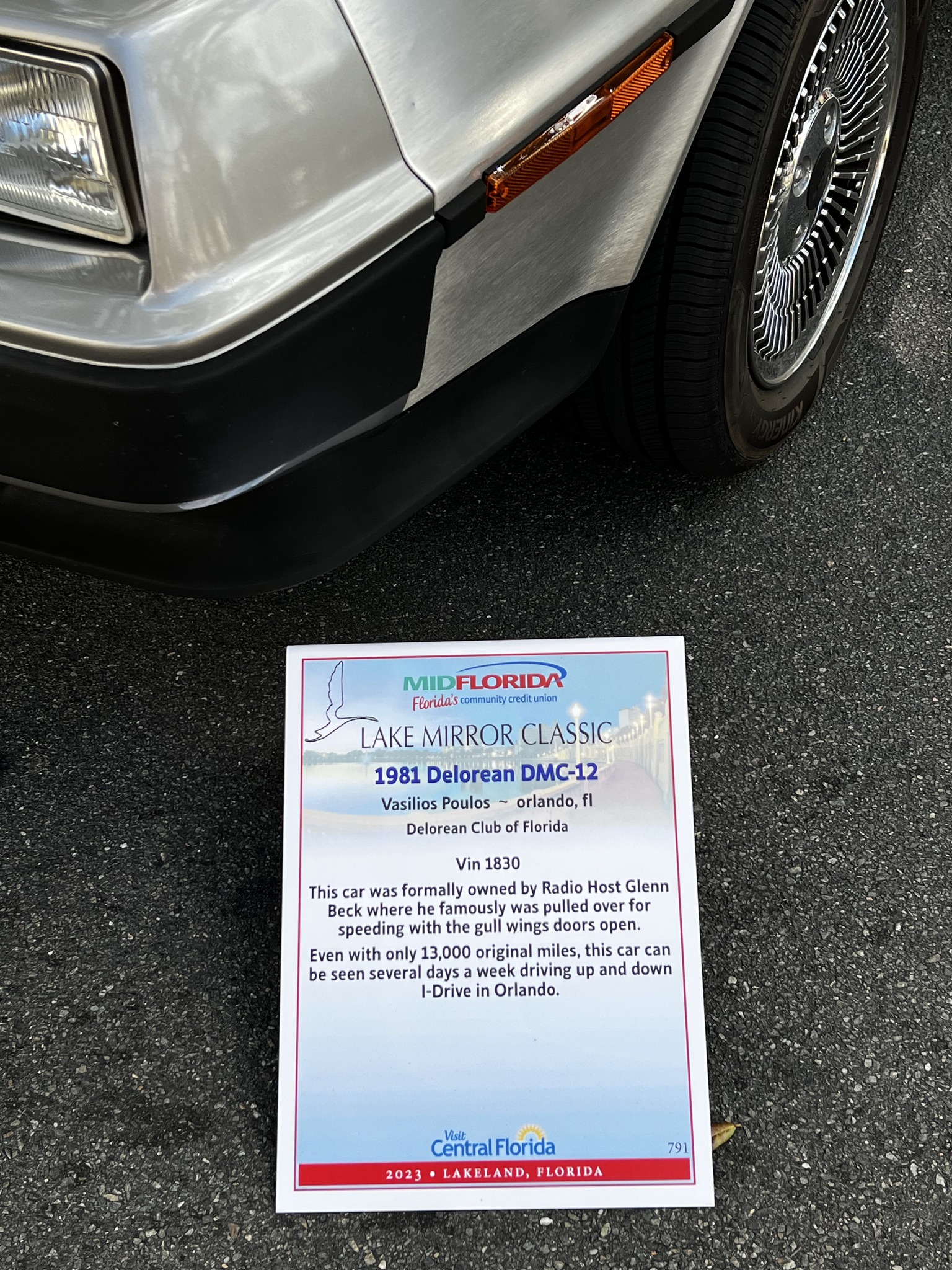 A professionally printed Lake Mirror Classic display sign in front of a DeLorean